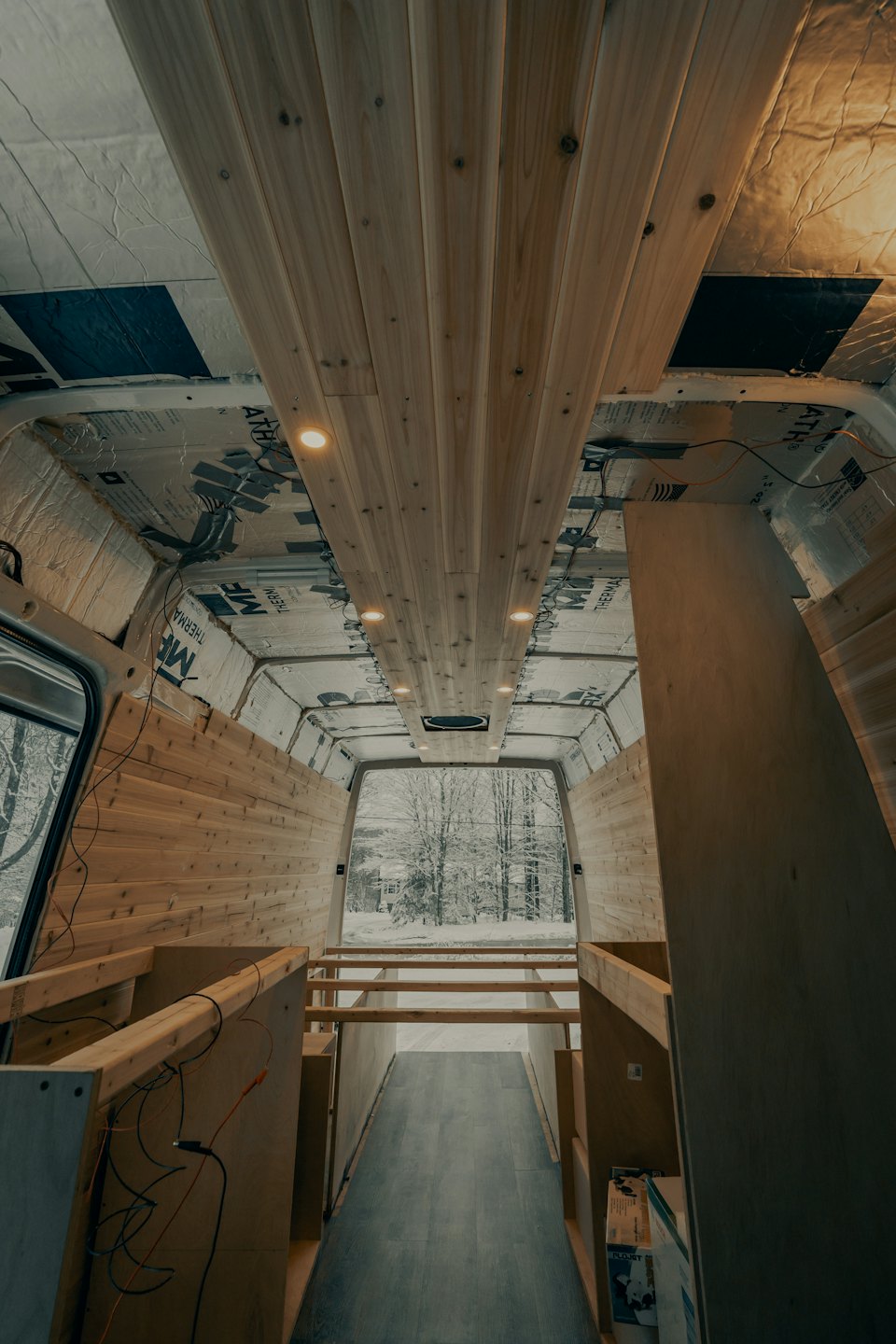 Wnętrze kampera w budowie z drewnianą boazerią i izolacją.